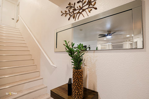 Bright, modern entry with chic mirror, wall art, and white staircase.