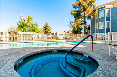 Sunny pool and hot tub oasis with seating in a landscaped courtyard