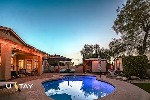 Resort-style backyard with lit pool, patio seating, and sunset ambiance