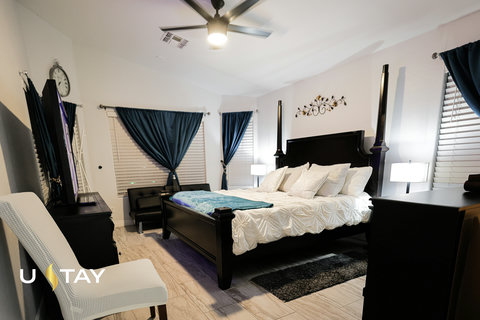 Elegant king bedroom with four-poster bed, TV, seating, and stylish decor