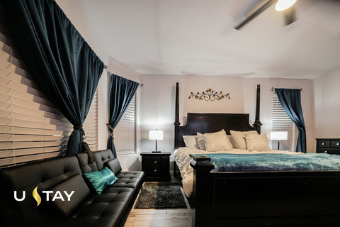Elegant bedroom with four-poster bed, chic seating, and warm lighting