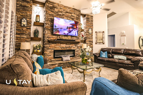 Cozy upscale living room with stone fireplace, big TV, and ample seating