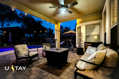 Covered patio with fire table, cozy seating, and poolside evening ambiance