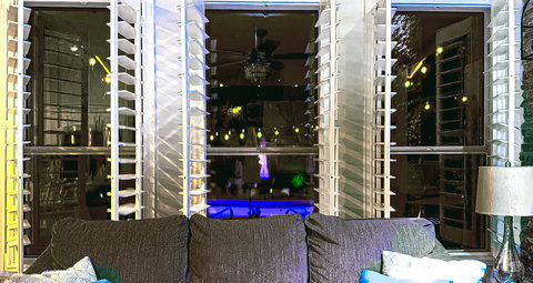 Cozy lounge with plantation shutters and sparkling pool views