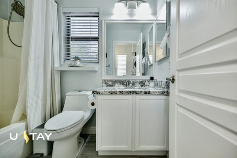Bright modern bathroom with granite vanity and tub-shower combo