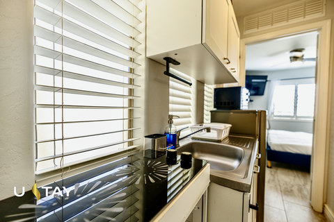 Bright kitchenette with cooktop, sink, and easy access to the bedroom