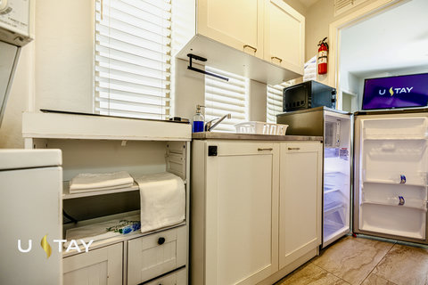 Bright kitchenette with mini fridge, microwave, sink, and handy storage