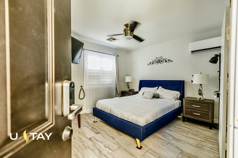 Bright modern bedroom with plush blue bed, TV, and efficient AC