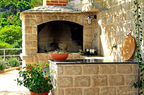 Large barbecue and table under arbour with everything needed for preparing meals