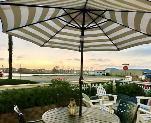 Patio Paradise: Sip drinks under the striped umbrella while watching the sunset over the harbor!