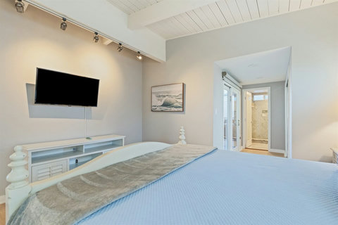 Primary King Suite Retreat to the luxurious primary suite featuring a plush king-sized bed, Smart TV, and balcony access to enjoy calming water views.