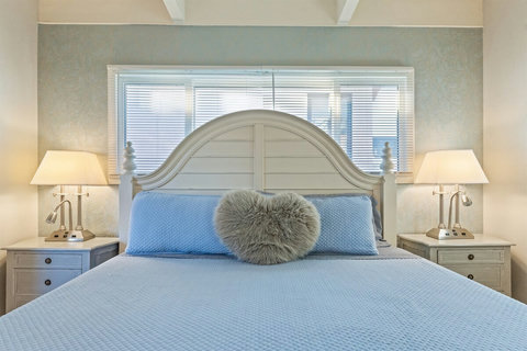 Primary King Suite Retreat to the luxurious primary suite featuring a plush king-sized bed, Smart TV, and balcony access to enjoy calming water views.
