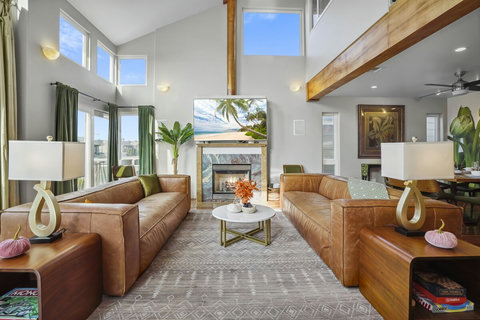 Bright living room with leather sofas, a gas fireplace, and stunning double-height ceilings.