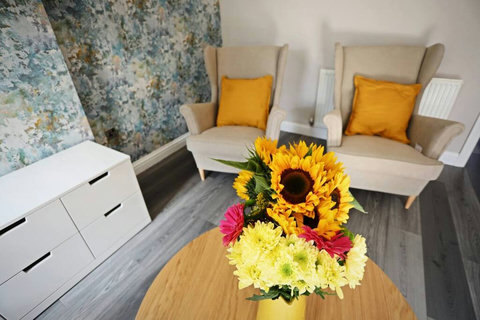 Living room featuring two-seater sofa, two armchairs, TV, storage space, table and chairs.