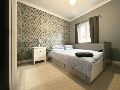 Second bedroom featuring extendable bed, bedside table, ample wardrobe space.