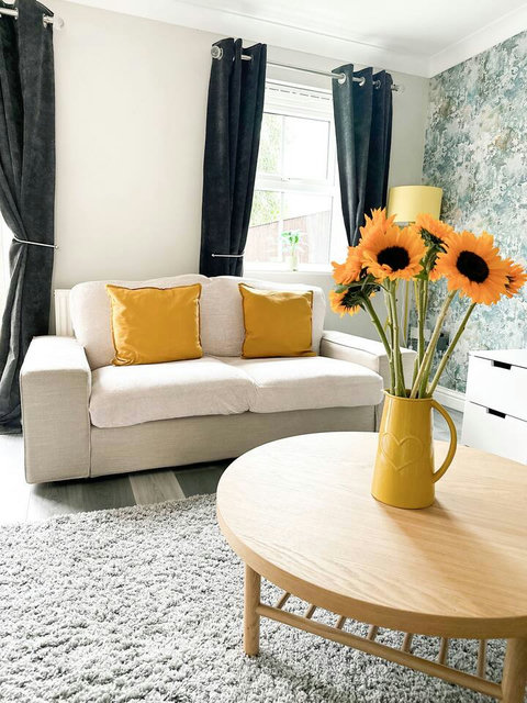 Living room featuring two-seater sofa, two armchairs, TV, storage space, table and chairs.