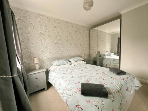 Main bedroom featuring queen size bed, wardrobe space, drawers, ensuite, and view of the garden.