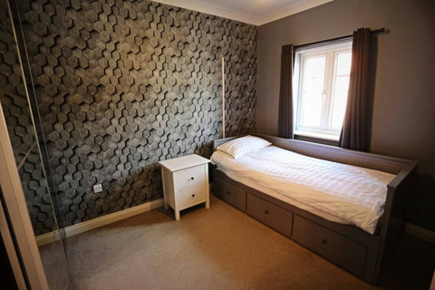 Second bedroom featuring extendable bed, bedside table, ample wardrobe space.