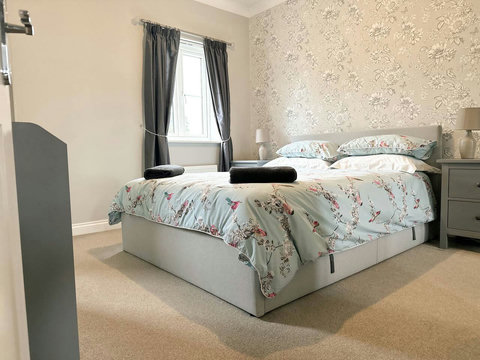 Main bedroom featuring queen size bed, wardrobe space, drawers, ensuite, and view of the garden.