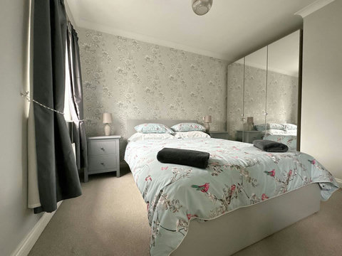 Main bedroom featuring queen size bed, wardrobe space, drawers, ensuite, and view of the garden.
