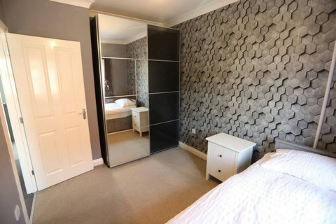 Second bedroom featuring extendable bed, bedside table, ample wardrobe space.