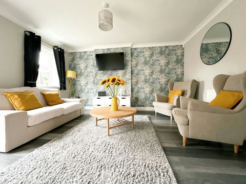 Living room featuring two-seater sofa, two armchairs, TV, storage space, table and chairs.