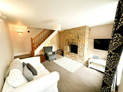 Living room, two-seater sofa, armchair, fire place, TV.