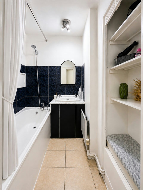 Clean full bathroom with bathtub, shower, fresh towels and convenient storage for toiletries and personal items.