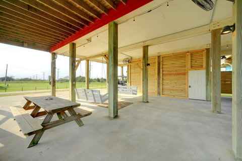 Shaded patio under the house with picnic tables and swings