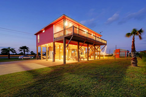 Lit up at dusk, with palm trees and a deck all the way around