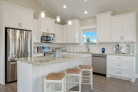 White kitchen with a granite island and stainless appliances