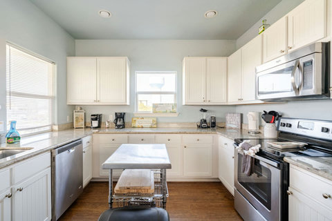 White kitchen with stainless appliances and a prep island