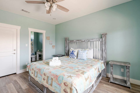 King bedroom with a rustic headboard and coastal quilt