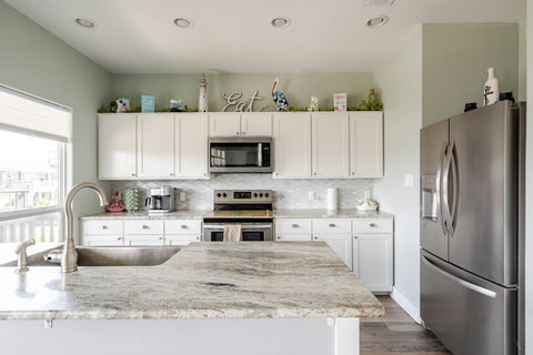 White kitchen with a granite island and farmhouse sink