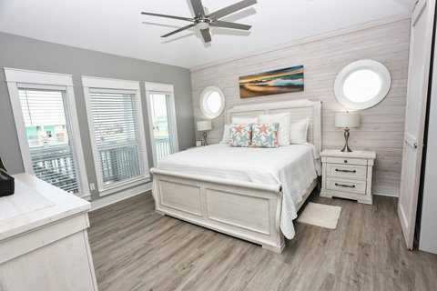 King bedroom with porthole windows and shiplap walls