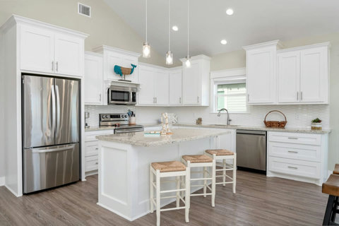 White kitchen with a granite island and stainless appliances