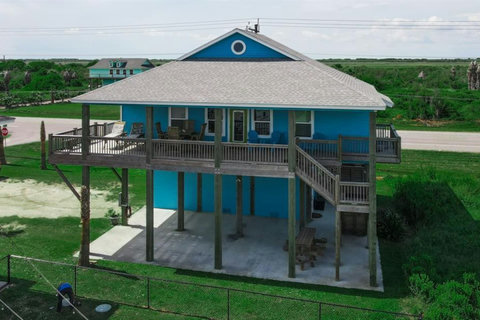 Raised beach home with a covered deck and shaded patio below