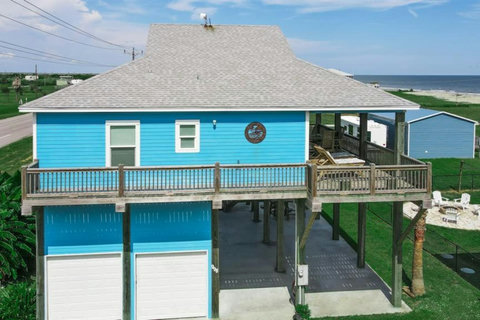 Beach house with a wraparound deck and the Gulf behind it
