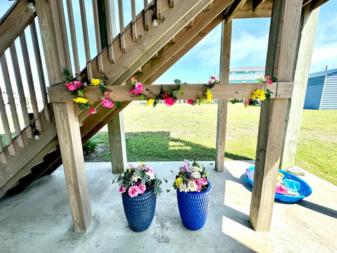 Patio under the stairs with flowers and a kiddie pool