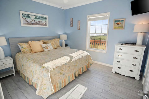 Bedroom with a large bed, dresser and TV