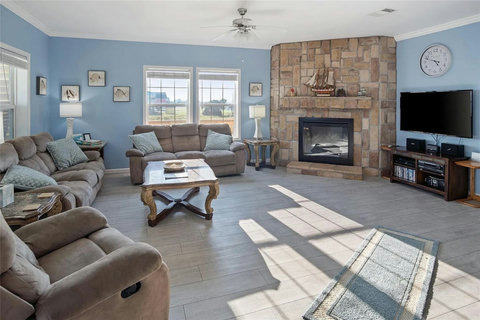 Living room with a stone fireplace, TV and recliners