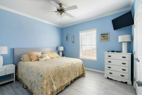 Bright bedroom with a dresser and wall TV