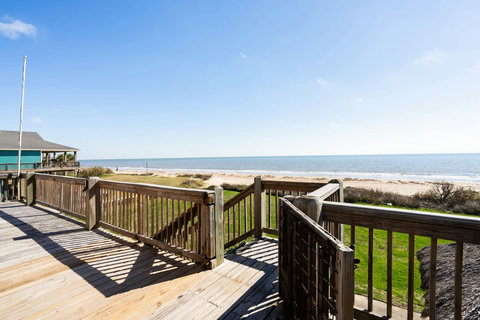 Deck steps lead toward the sand