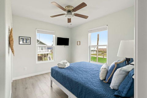 Bedroom with a TV and views out two windows