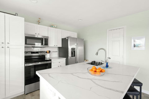 White kitchen with a quartz island and stainless appliances