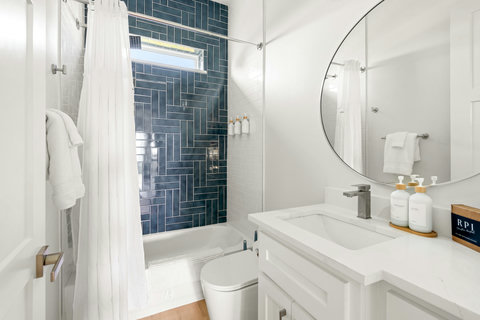 Hall bath with blue tile and a round mirror