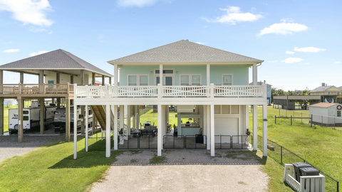 Raised beach house with a covered deck and shaded patio below