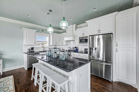 White kitchen with granite counters and an island with bar stools