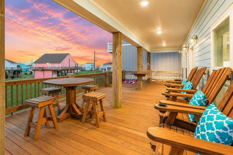 Covered deck with tall Adirondack chairs and a bistro table