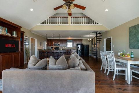 Open living, dining and kitchen under a vaulted ceiling